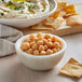 A bowl of hummus with chickpeas and parsley.