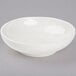 A Tuxton eggshell white salad bowl with a small rim on a gray surface.
