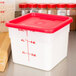 A white Cambro CamSquares polyethylene food storage container with a red lid.