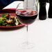 A close-up of a Chef & Sommelier balloon wine glass filled with red wine on a table.