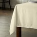 An Intedge ivory rectangular tablecloth on a wooden table.