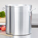 A large silver Vollrath Wear-Ever stock pot with handles on a counter full of vegetables.