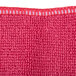 A close up of a red microfiber cloth with white stitching.