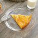 A piece of pie on a WNA Comet clear plastic plate with a fork next to a glass of milk.