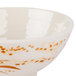 A close-up of a white Thunder Group Gold Orchid melamine rice bowl with brown spots.