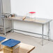 An Advance Tabco stainless steel open base work table with bowls and a rolling pin on it.