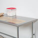 An Advance Tabco stainless steel work table with an open base on a counter in a professional kitchen.