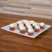 A CAC porcelain serving platter with red velvet cupcakes with white frosting.