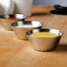 Three American Metalcraft hammered stainless steel sauce cups filled with different sauces on a table.