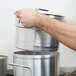 A person holding a Vollrath aluminum inset for a double boiler over a stove.