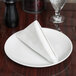 A white plate with a folded silver Hoffmaster Prestige linen-like napkin on it.