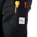 A pocket on the sleeve of a black Mercer Culinary chef jacket with cloth buttons.