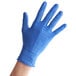 A hand wearing a blue Noble Products nitrile glove.