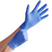 A pair of blue nitrile exam gloves being worn on hands.