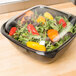 A clear plastic dome lid on a salad in a plastic container.