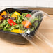 A salad in a Sabert clear plastic container with a clear dome lid.
