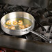 A Vollrath Wear-Ever saute pan with shrimp cooking in it on a stove.