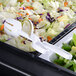 A salad on a table with white plastic salad tongs.