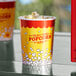 A yellow Carnival King popcorn cup filled with popcorn on a table.