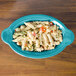A turquoise Fiesta oval china baker filled with pasta and vegetables.