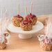 A group of caramel apples on a 10 Strawberry Street white porcelain cake stand.
