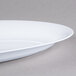 A close up of a white Fineline oval tray with a rim.