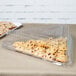 A Fineline clear plastic triangular tray with cookies on a table.