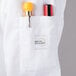 A white Mercer Culinary chef jacket with a pocket holding two pens.