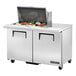 A True stainless steel refrigerated sandwich prep table with two doors on a counter with a food tray.