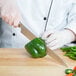 A person using a Mercer Culinary MX3 Sujihiki knife to cut a green bell pepper.