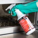 A hand in green gloves spraying Solwave Fusion Oven Cleaner into an oven.