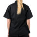 A woman wearing a Mercer Culinary Genesis black chef jacket with short sleeves.