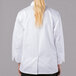 A woman wearing a white Mercer Culinary chef jacket with long sleeves.