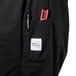 A black Mercer Culinary Genesis chef jacket with a pocket and pen on the counter.