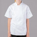 A woman wearing a white Mercer Culinary chef jacket with short sleeves.