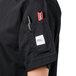 A person wearing a Mercer Culinary Genesis black chef jacket with a pen in the pocket.