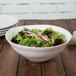 A 10 Strawberry Street white stoneware serving bowl filled with salad including lettuce, broccoli and radishes.