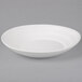 A white stoneware plate with a matte wave design.