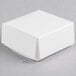 A 2 1/2" x 2 1/2" white candy box with a lid on a gray surface.