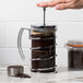 A person using a Libbey stainless steel French press to make coffee.