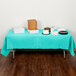 A table with a teal lagoon tablecloth and food on it.