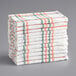 A stack of white waffle-weave dish cloths with orange stripes.