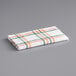 A white waffle-weave dish cloth with orange and green stripes.