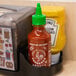 A case of Huy Fong Sriracha Hot Chili Sauce bottles on a shelf.