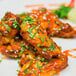 A plate of chicken wings with Huy Fong Sriracha sauce and green garnish.