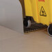A yellow Advance Tabco mop bucket with wheels sits on a metal floor.
