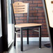 A Lancaster Table & Seating black bistro chair with natural wood seat and back sitting on a restaurant dining area table.