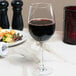 An Arcoroc Excalibur wine glass filled with red wine on a table.