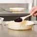 A person stirring Lucky Leaf blueberry pie filling with a wooden spoon.