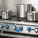 A Globe countertop gas hot plate with three large metal pots on it.